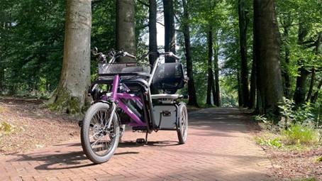 Foto van een duofiets in een groene omgeving. Per locatie kan het type duofiets verschillen.
