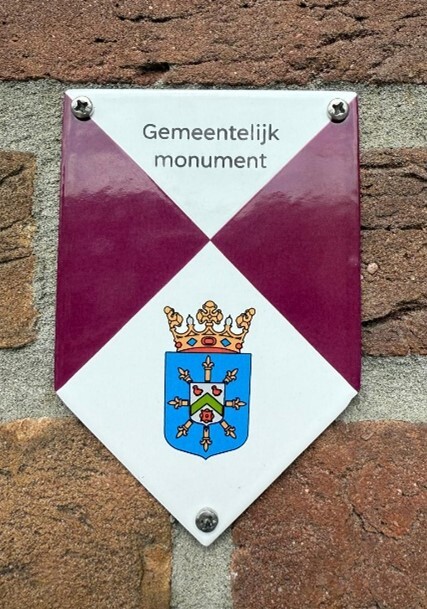 Schildje voor een gemeentelijk monument, in paars-witte vlakken, met onderaan een wapen. Dit is het type gemeentelijk monumentenschildje dat door de gemeente Maashorst wordt gebruikt.