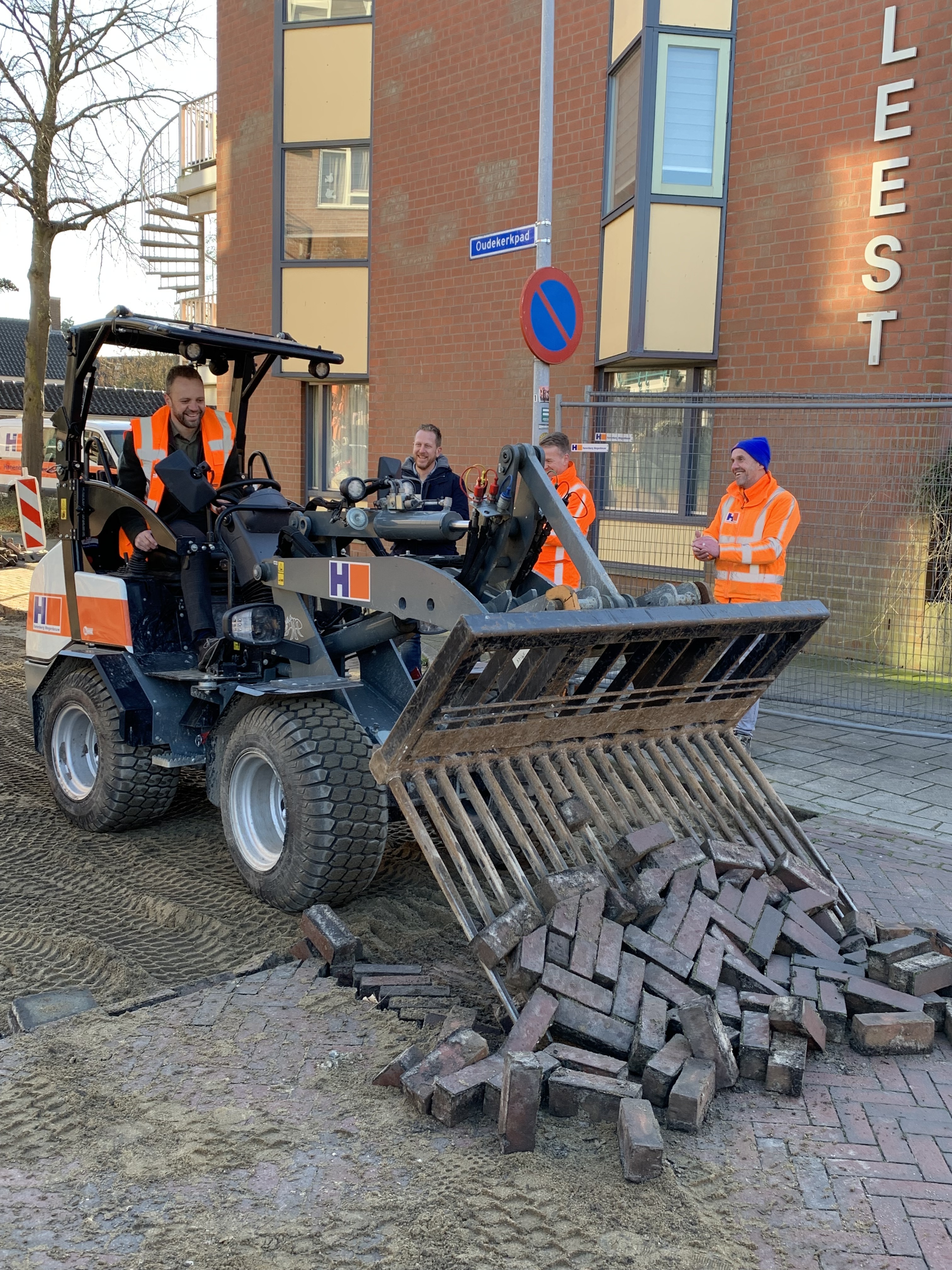 Wethouder Jeroen van de Heuvel in een elektrische mini-loader aan de slag met het straatwerk in het Oudekerkpad.